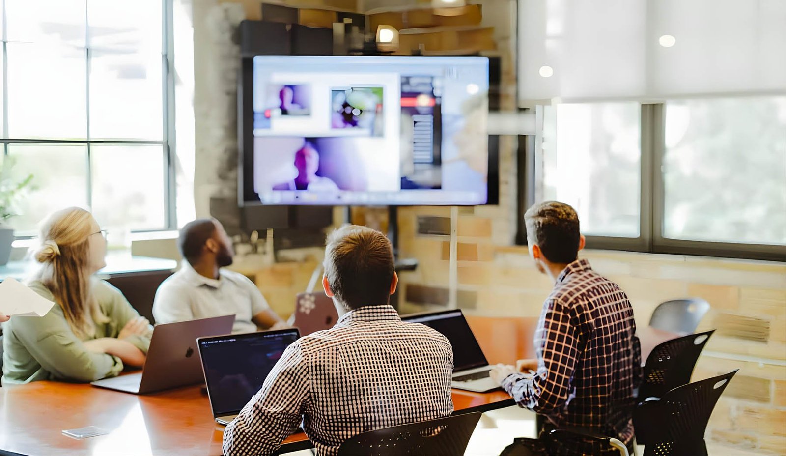 People in a meeting room videoconferencing with a remote team